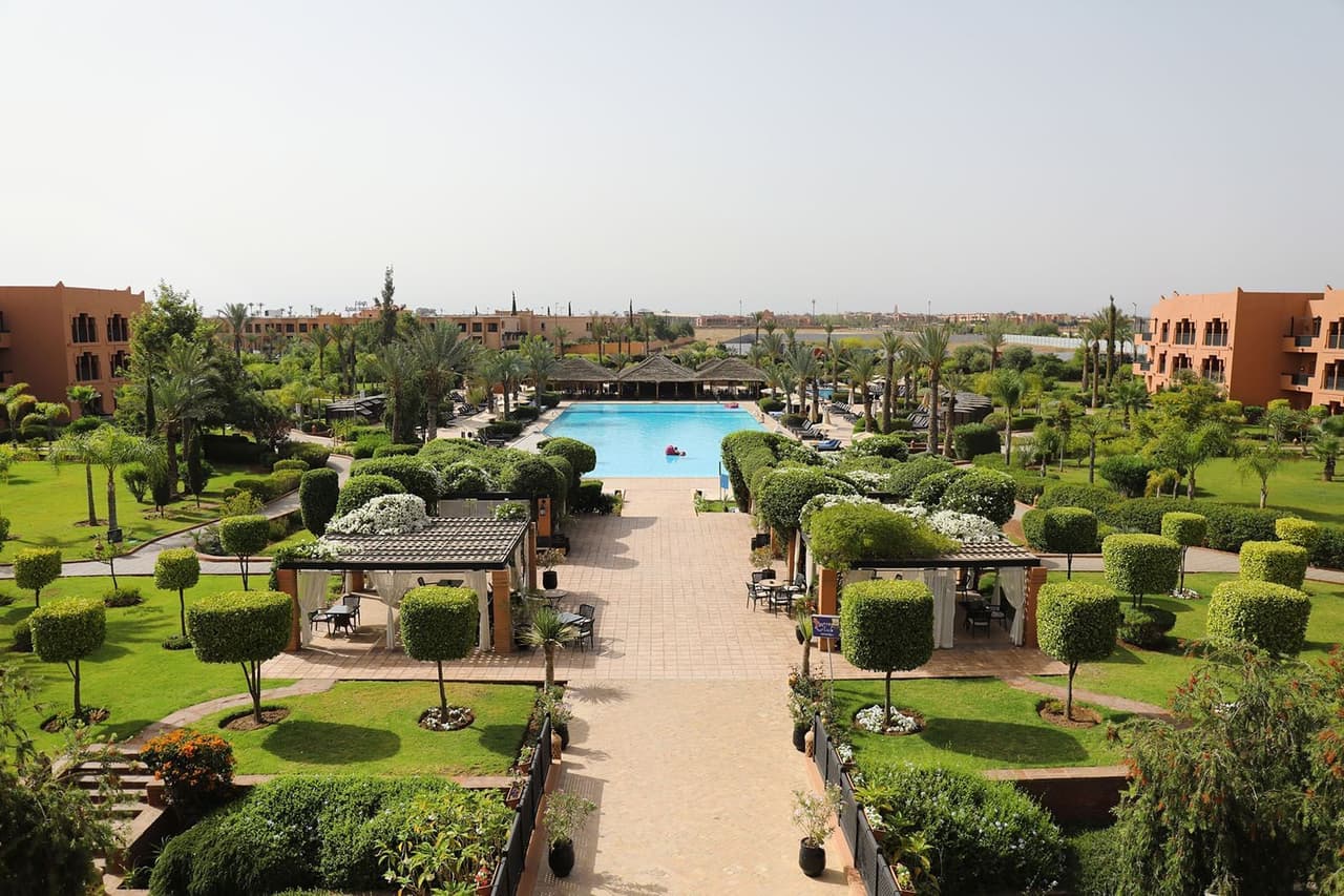 A garden walkway leading down to the large pool at the Kenzi Menara Palace