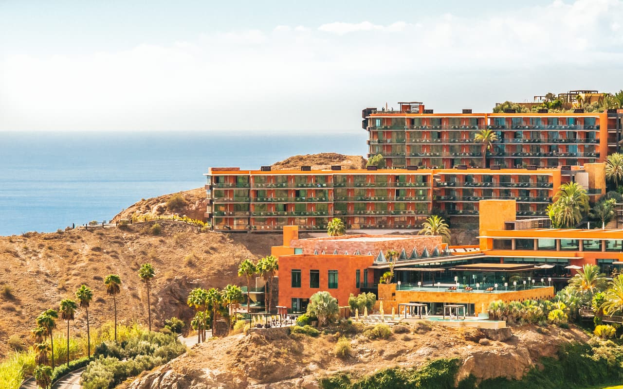 Salobre Hotel's terracotta buildings on the hillside, with palms and the ocean beyond